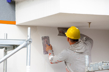 Construction workers plaster the facade of the house. Application Of Facade Plaster.