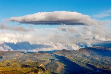 A cumulus cloud above fall forest in a mountains