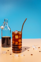 Iced coffee in glass and bottle on beige background,hard light