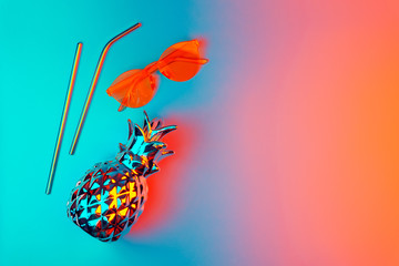 Summer creative background, decorative pineapple, sunglasses, cocktail straws in neon light