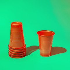 Red plastic disposable cups on mint background,trendy hard shadows