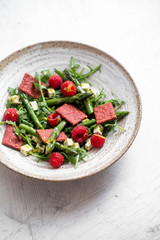 salad with asparagus, arugula, tofu and raspberries in rustic plate