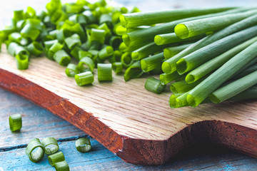 Sliced green onion rings on a cutting board on a background of old blue boards.
