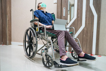 Obraz premium woman wearing medical mask while sitting on wheelchair a hold digital tablet at hospital