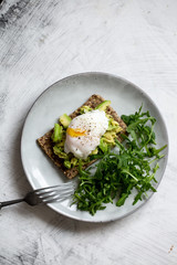 Tasty sandwich with poached egg and avocado on mrble background with copy space