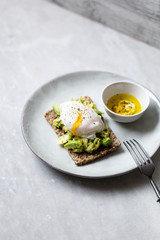 Tasty sandwich with poached egg and avocado on mrble background with copy space