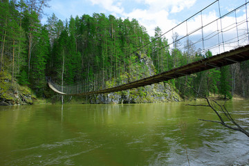 suspension bridge over a river in the spring forest