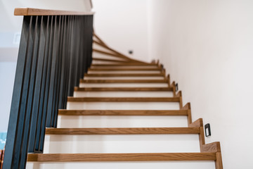 Fototapeta na wymiar stylish wooden stairs in the apartment with handmade black metal railings