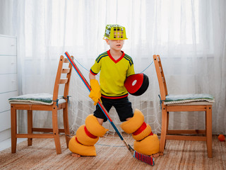 A child boy plays hockey at home having made a form with his own hands from improvised home tools...