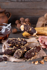 A child holds a healthy homemade dessert in his hands frozen Chocolate Covered Bananas and nuts
