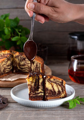 Marble cake with chocolate on a plate. Chocolate dripping from a spoon