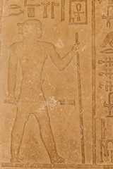Ancient egyptian paintings and hieroglyphs carved on the stone wall