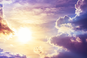Bright sun with orange light in sky and purple light on clouds