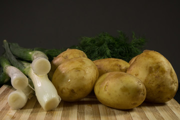 Raw fresh organic potatoes on black wooden table against dark background.