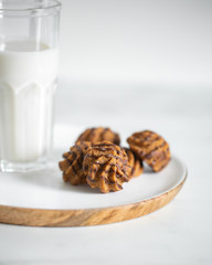 cookies on white wooden plate with glass of milk