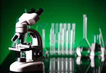 Coronavirus pandemic theme. Science research concerning fast covid tests and anti-covid vaccine. Beakers and test tubes on green background in laboratory.