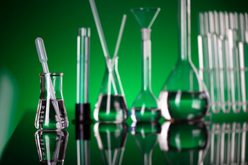 Coronavirus pandemic theme. Science research concerning fast covid tests and anti-covid vaccine. Beakers and test tubes on green background in laboratory.