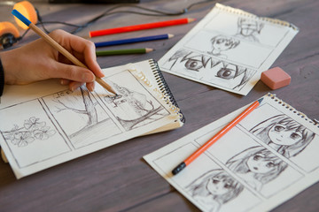 Artist drawing an anime comic book in a studio. Wooden desk, natural light. Creativity and...