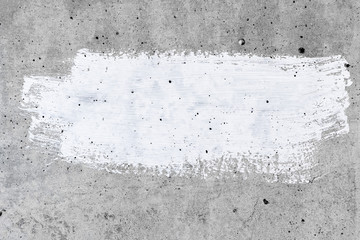 A gray concrete wall with white paint smears in the center. Grey background with white paint border with text space.