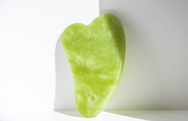 Gua sha tool in natural gemstone of green Jade at white background