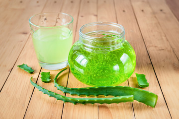 Fresh juice and aloe Vera gel with fresh aloe leaves on a wooden background