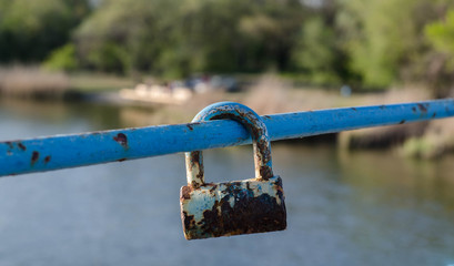 Old padlock. A padlock hangs on the railing. Rusty metal.