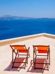 Two chairs on terrace and amazing Santorini volcano view. Santorini, Cyclades, Greece.