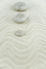 Zen garden. Pyramids of white and gray zen stones on the white sand with abstract wave drawings. Concept of harmony, balance and meditation, spa, massage, relax.
