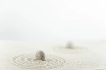 Foto auf Acrylglas Zen Garten. Pyramiden aus weißen und grauen Zen-Steinen auf dem weißen Sand mit abstrakten Wellenzeichnungen. Konzept der Harmonie, Balance und Meditation, Spa, Massage, Entspannung. © strigana