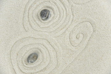 Zen garden. Pyramids of white and gray zen stones on the white sand with abstract wave drawings....