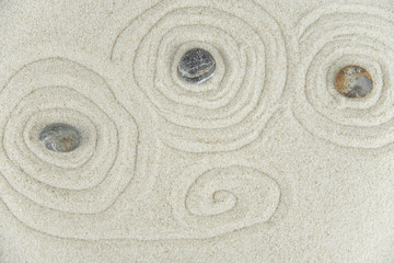 Zen garden. Pyramids of white and gray zen stones on the white sand with abstract wave drawings. Concept of harmony, balance and meditation, spa, massage, relax.