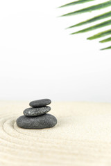 Obraz na płótnie Canvas Zen garden. Pyramids of white and gray zen stones on the white sand with abstract wave drawings. Concept of harmony, balance and meditation, spa, massage, relax.