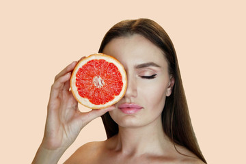 Young woman with grapefruit cut in half, healthy life concept . photo of attractive girl holding a cut piece of pomelo in her hands. Healthy and proper nutrition
