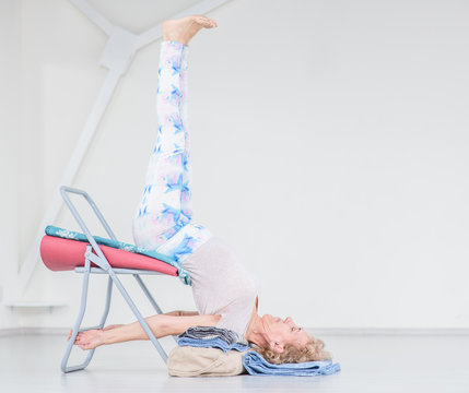 Senior Woman Doing Yoga With Chair. Stretching Exercises