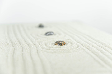 Zen garden. Pyramids of white and gray zen stones on the white sand with abstract wave drawings. Concept of harmony, balance and meditation, spa, massage, relax.