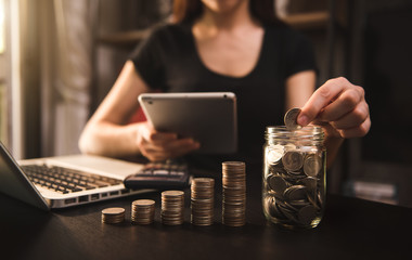 businesswoman holding coins putting in glass with using smartphone and calculator to calculate  concept saving money for finance accounting
