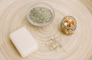 Eco-friendly cosmetics on the background of a wooden tray. pieces of dried orange in a transparent jar, handmade ubtan and natural soap.

