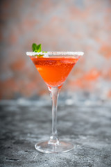 Red cocktail with bloody oranges in martini glass on the rustic background