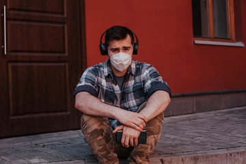 a man sits in a mask and listens to music in the city
