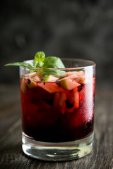 Old fashioned cocktail with blackberry liqueur and apple slices on rustic background. Selective focus. Shallow depth of field.