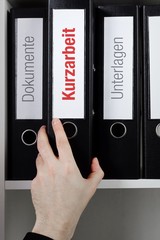 Kurzarbeit – Finanzen/Statistik. Ordner im Büro-Regal. Hand greift Unterlagen im Schrank....