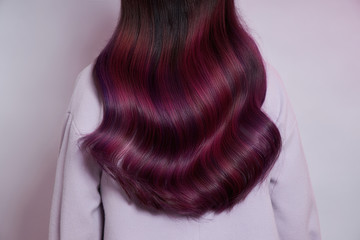 Portrait of a woman with bright colored flying hair, all shades of purple. Shiny Healthy colored Hair coloring, beautiful lips and makeup. Sexy girl with long hair styling