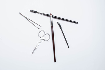 Makeup brushes, scissors, tweezers, mascara on a white background. Makeup. Beauty and fashion.