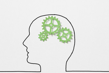 Drawn outline of human head with green clockwork as a working brain.