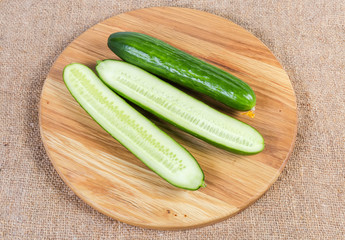 Whole and halves cucumbers on the round wooden cutting board