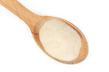 Uncooked semolina in wooden spoon on a white background