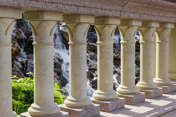 Fragment of stone balustrade against the small waterfall