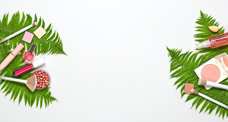 Beauty cosmetic makeup background. Fashion woman make up product, brushes, lipstick, tropical leaf, flat lay. Creative concept. Cosmetology make-up accessories on white, border, top view.