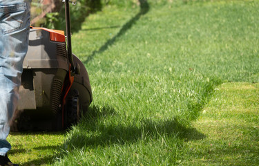 Man moves with lawnmower mows green grass