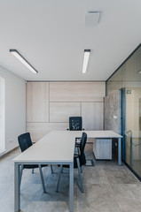 Interior of small new empty office space with desks and chairs and glass wall